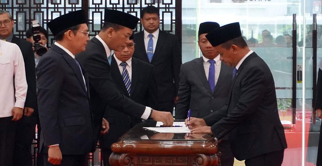 Left to right: Ahmad Erani Yustika, newly appointed Secretary General of the Ministry of Energy and Mineral Resources, and Yudhiawan, the new Inspector General, sign their appointment documents, witnessed by Minister of Energy and Mineral Resources Bahlil Lahadalia. (Lucky Ebenhaezer)